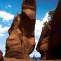Photographie couleur montrant de hautes formations rocheuses rouges et deux personnes sur la plage