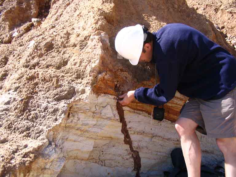 Photographie couleur d’un homme devant un rocher brun et blanc