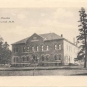 Black and white postcard of large, square stone building with curved window casings