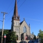 Colour photograph of stone church with large steeple on left