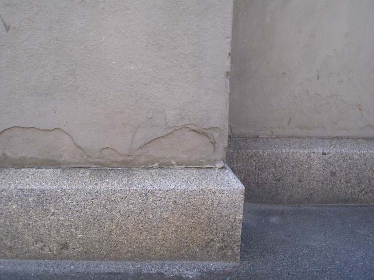 Colour photograph of slab of gray rock at base of building column