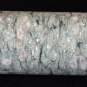 Image couleur d’un échantillon de roche grise en forme de tube marbré de blanc et de rose